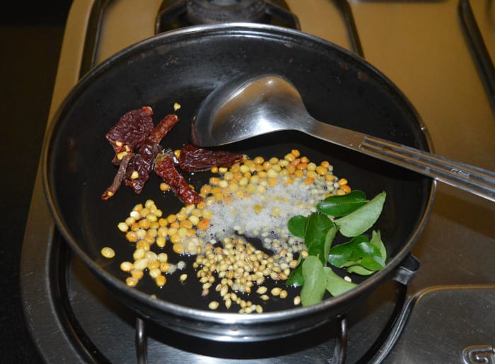 Step one: Heat oil in a deep-bottomed pan. Add split chickpeas, white lentils, coriander seeds, broken dry red chilies, and curry leaves. Over medium heat, saute until the split chickpeas and lentils become golden brown and crispy.