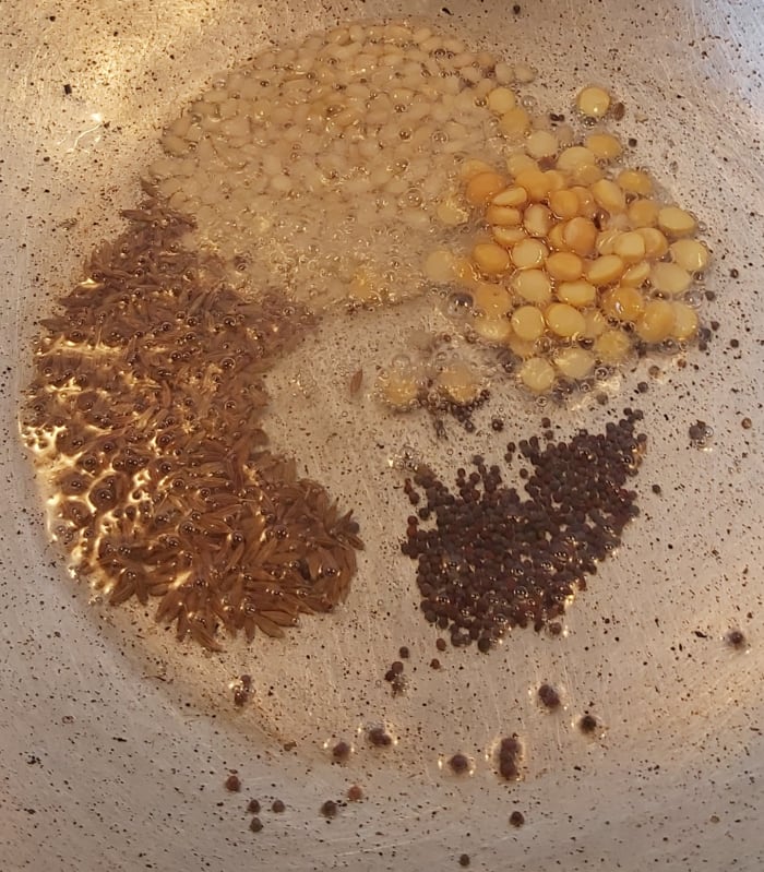 In a pan, heat 1-2 tablespoons of oil. Splutter 1/2 teaspoon of mustard seeds and 1 teaspoon of cumin seeds. Add 1 tablespoon of split black gram (urad dal) and Bengal gram.