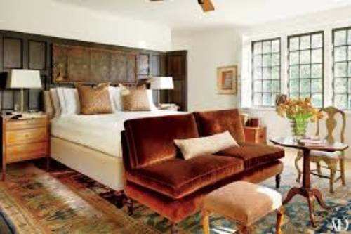 The master bedroom has a leather headboard, a Turkish wool rug, the ceiling fan, a velvet sofa and the lovely windows.