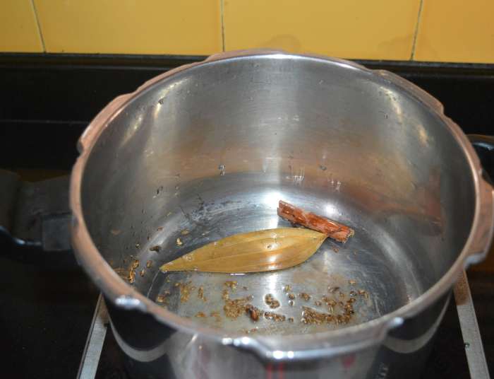 Step one: Add ghee or oil, cumin seeds, bay leaf, cloves, cinnamon stick, and cardamom to a pressure cooker. Heat it. Saute the mixture over medium heat until the cumin crackles.