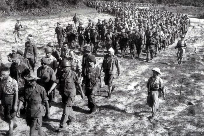 Captured French soldiers from the battle of Dien Bien Phu, escorted by Vietnamese troops, walk to a prisoner-of-war camp