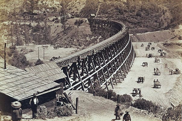 Chinese labourers shifting fill by hand next to a trestle. The fill would eventually replace the bridge.