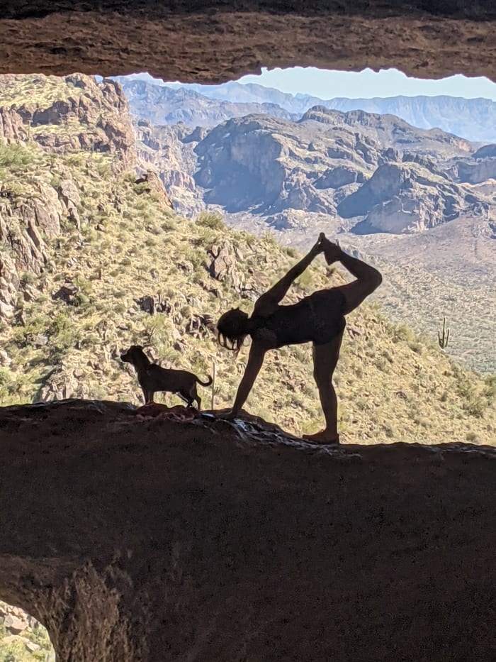 A visitor to Wave Cave doing a yoga position with her dog in the rock across the front of Wave Cave