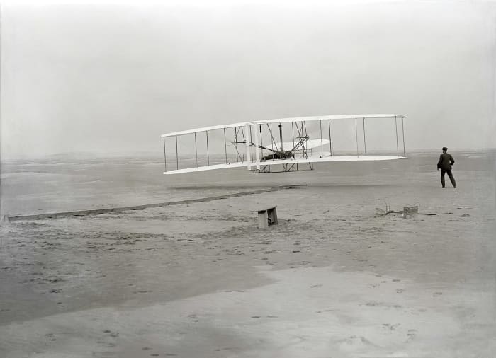 First flight of the Wright Flyer, December 17, 1903, Orville piloting, Wilbur running at wingtip