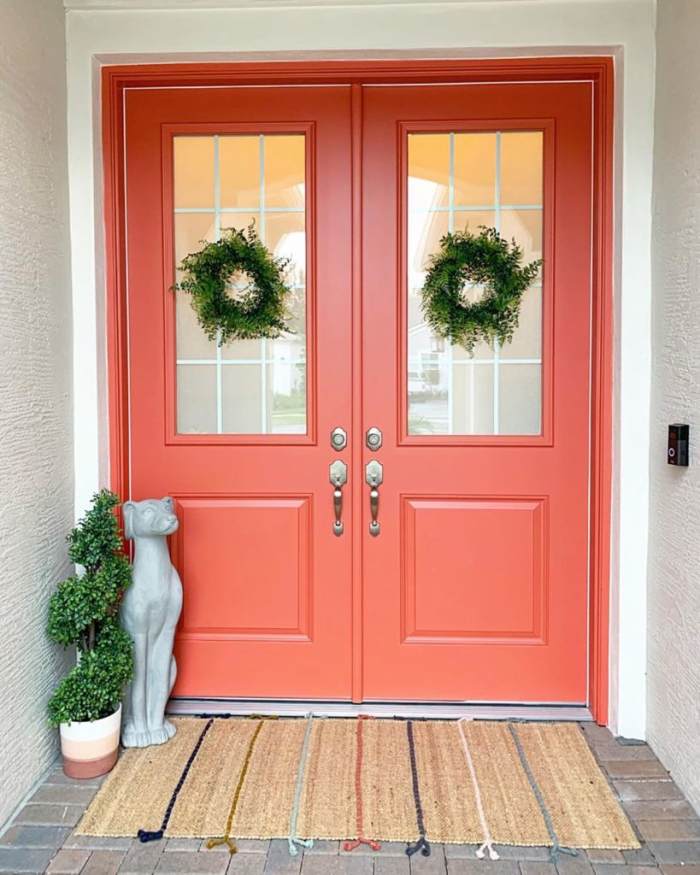 A splash of coral color during the year is a pleasant way to make your home feel bright and welcoming. The very coral double doors make a big statement, and they look great with natural potted greenery and jute rugs.