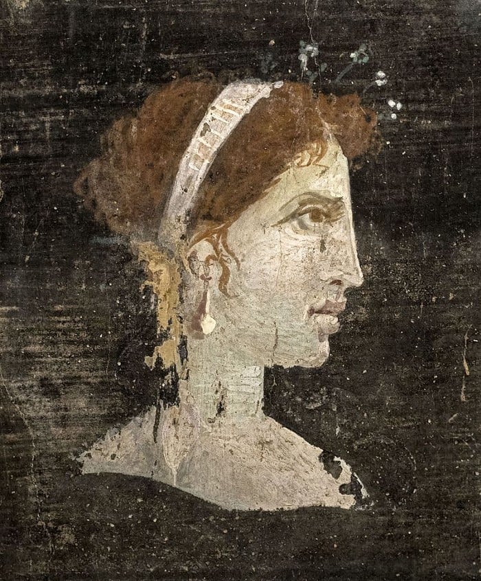 Most likely a posthumous painted portrait of Cleopatra VII of Ptolemaic Egypt with red hair and her distinct facial features, wearing a royal diadem and pearl-studded hairpins, from Roman Herculaneum, Italy, 1st century AD