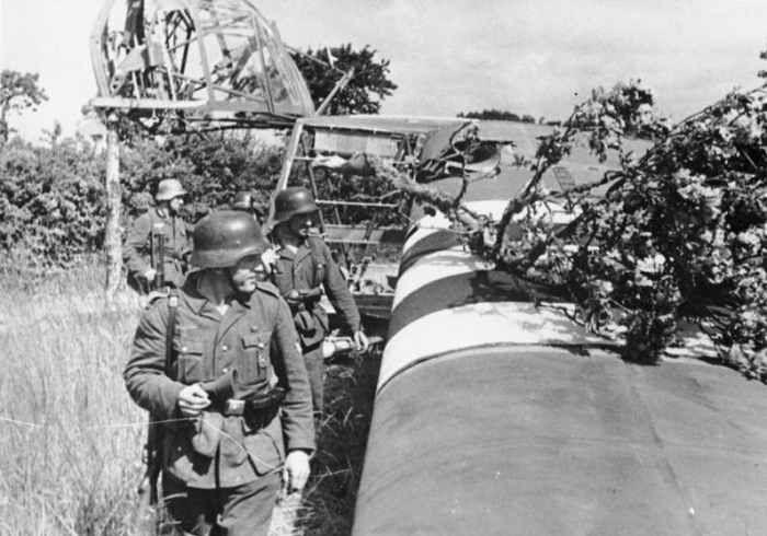 An abandoned Waco CG-4 glider is examined by German troops the morning of the D-Day landings.