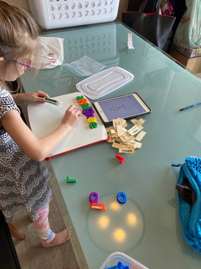 My daughter working on her own after school with our “tools” to learn her reading and writing. 20 minutes a day can be fun and makes a big difference. Note the ordinary “tools”, white board, alphabet letters. Things many parents already have.