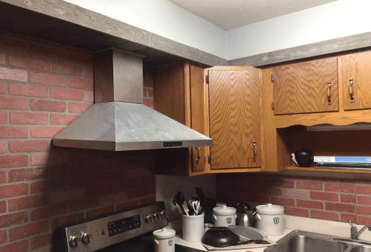 If you're good at metal working, you can easily cut the chimney to make the range hood fit in the available space.