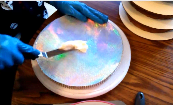 I'm going to show you how to make incredible display boards for yourself, just like this one. You won't believe how easy it is! Place a small dollop of buttercream in the center and spread it out thinly with the offset spatula.