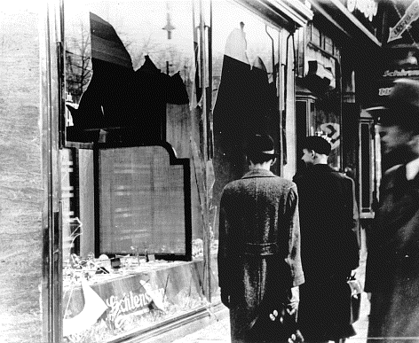 Germans pass this Jewish-owned business destroyed during "the night of broken glass" in Berlin, Germany. This occurred on November 10, 1938.