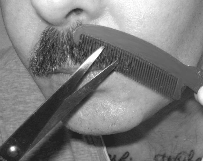 Tidying a mustache: Run the comb lightly over one half of the mustache. Hairs that don't lie flat will poke through its teeth.