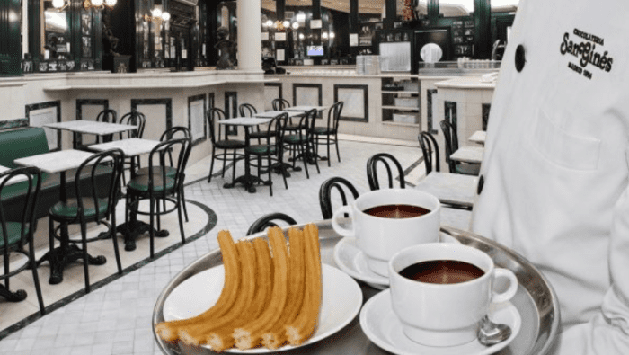 Inside view of El Café San Gines as a server, or un mesero, delivers a plate of churros con chocolate.