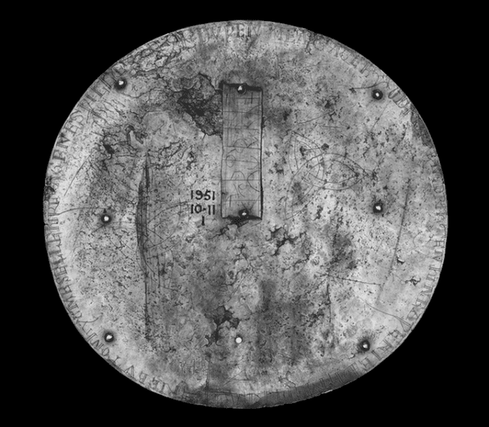 The rear of the brooch, which features triquetra etchings as well as the inscription and runic plate.