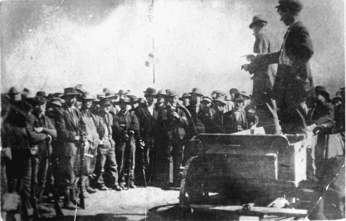 UMWA labor union organizers address coal miners on strike against CF&I, in Ludlow, Las Animas County, Colorado; United States flags are over the crowd.