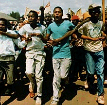 Youth at a comrade's funeral and holding a banner aloftYouth in 1976 holding the frontline from the heaving masses behind them