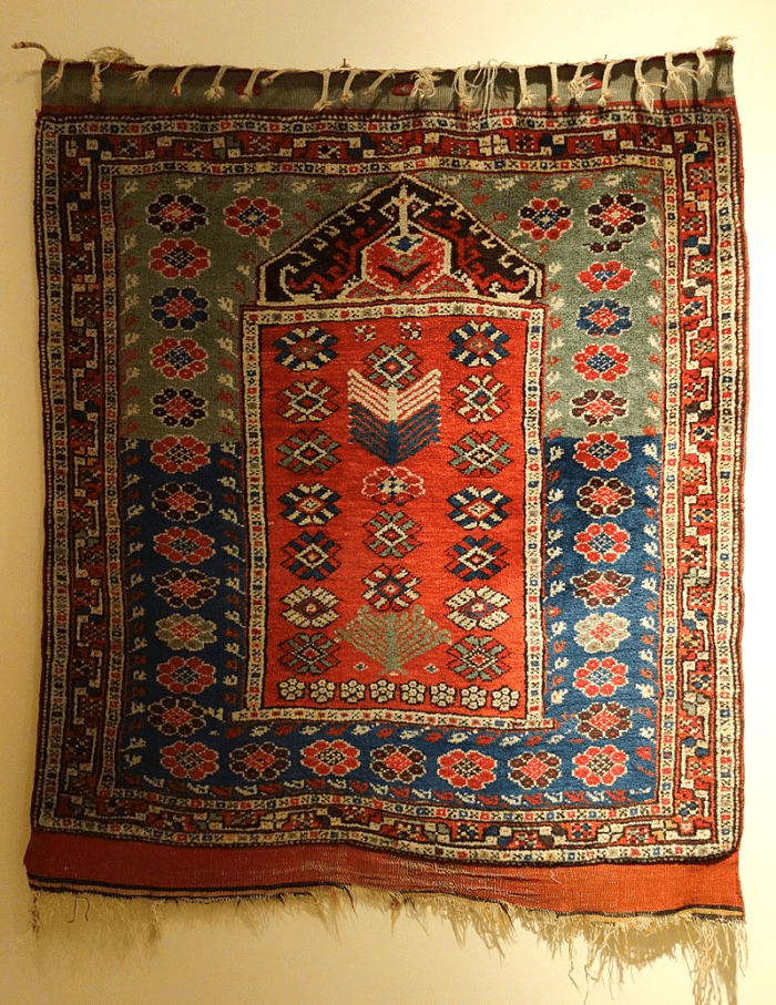 The niche at the top of the rug represents the mihrab and the direction of prayer.