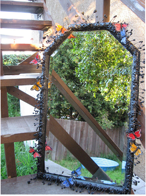 This mirror started with a plain frame, and the revamp consisted of a coating of black spray paint, plus faux flower stamens (I think) and fabric butterflies stuck all over to create a cool effect.