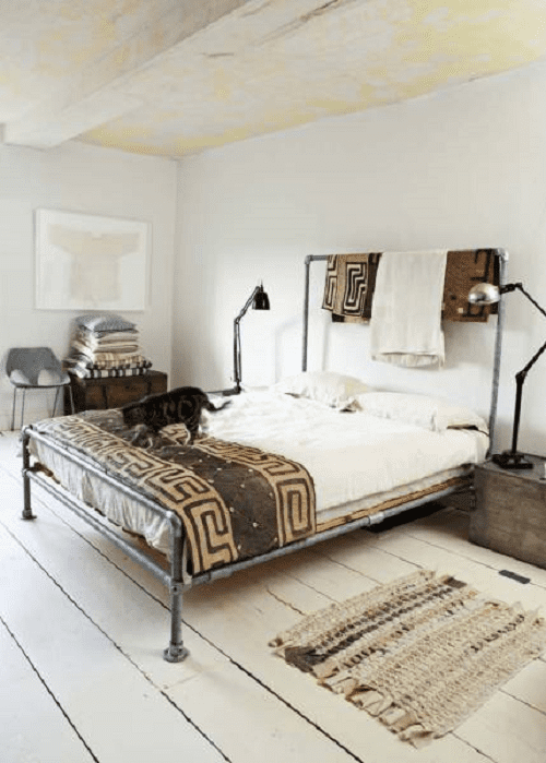 A modern minimalist bedroom layout with a rustic floor finish, modern chair, and contemporary table/reading lamps. The setting is typical of an ethnic theme.