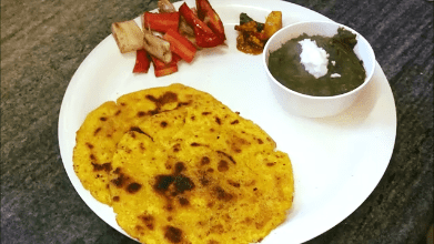Traditional Punjabi meal of makki ki roti served with sarson ka saag, sweet and sour pickle and salad