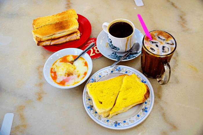 A traditional Malaysian breakfast of Toast, Half boiled eggs and Coffee.