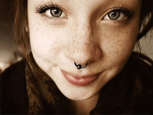 une femme à taches de rousseur avec un piercing au septum