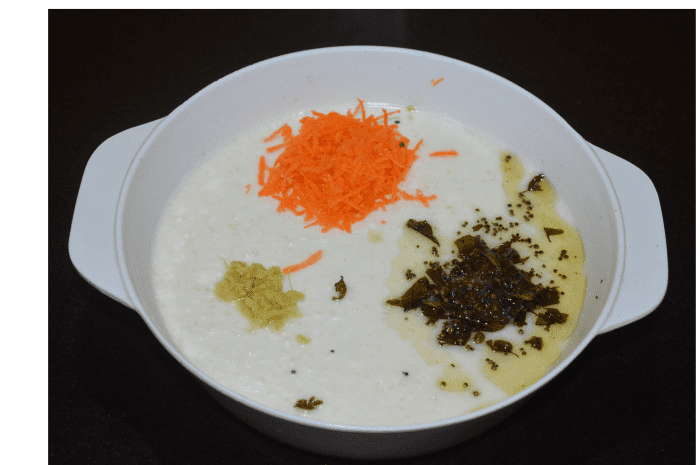 Step two: During resting, the batter ferments and increases in volume. Check for consistency. Add water and mix well to get the dropping consistency. Add grated carrots and grated ginger. Also, add the tempering as per instructions. Mix well.