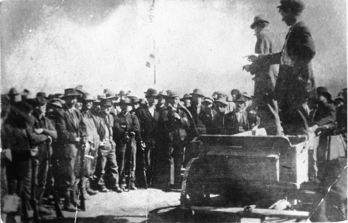 UMWA labor union organizers address coal miners on strike against CF&I, in Ludlow, Las Animas County, Colorado; United States flags are over the crowd.