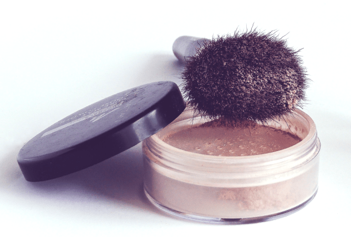 A loose powder container with a perforated divider.