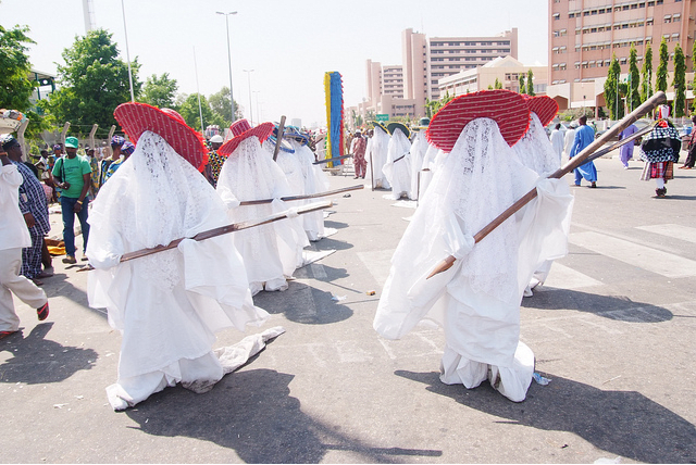 The Eyo masquerade's costume is one of splendour. White flowing robes, lace veils, prominent hats (different groups wear different hats), and the famous Opambata, a long thick cane that's a part of the ensemble.