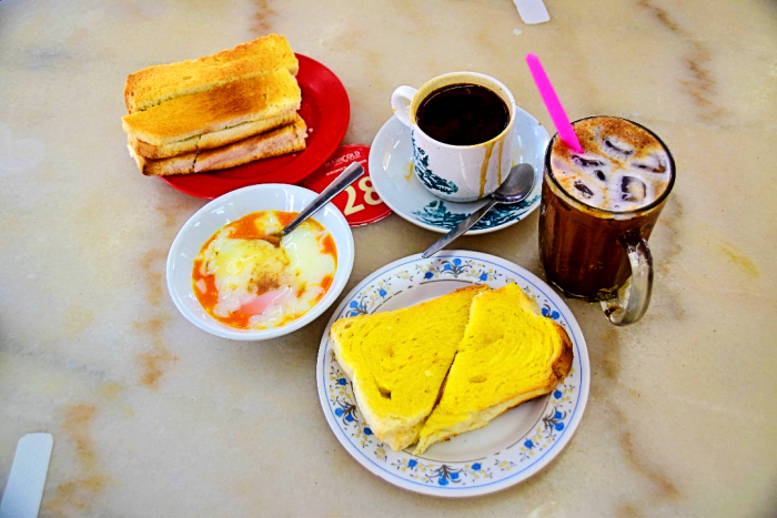 A traditional Malaysian breakfast of Toast, Half boiled eggs and Coffee.