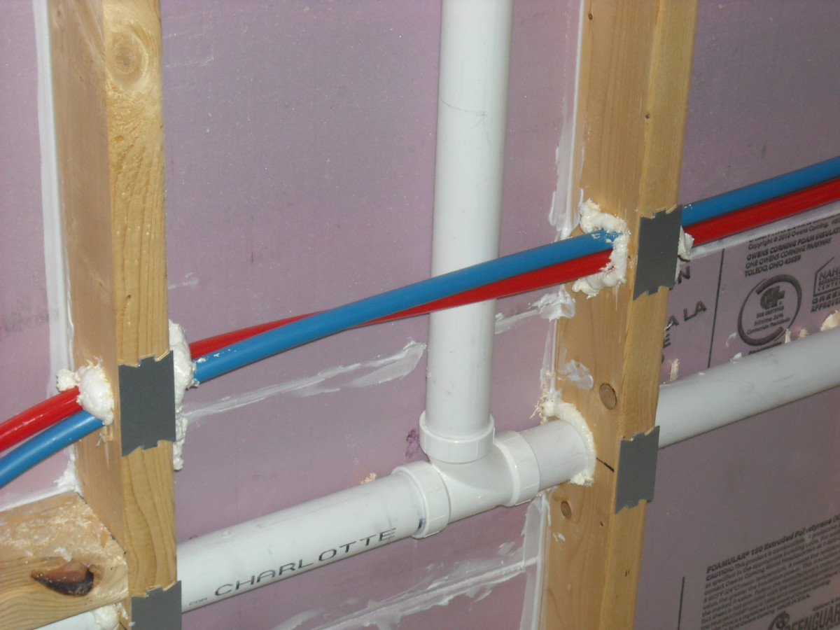 Hot and cold PEX water lines run through the same hole in a stud wall. This is not a typical installation; both pipes should have their own holes to pass through the framing.