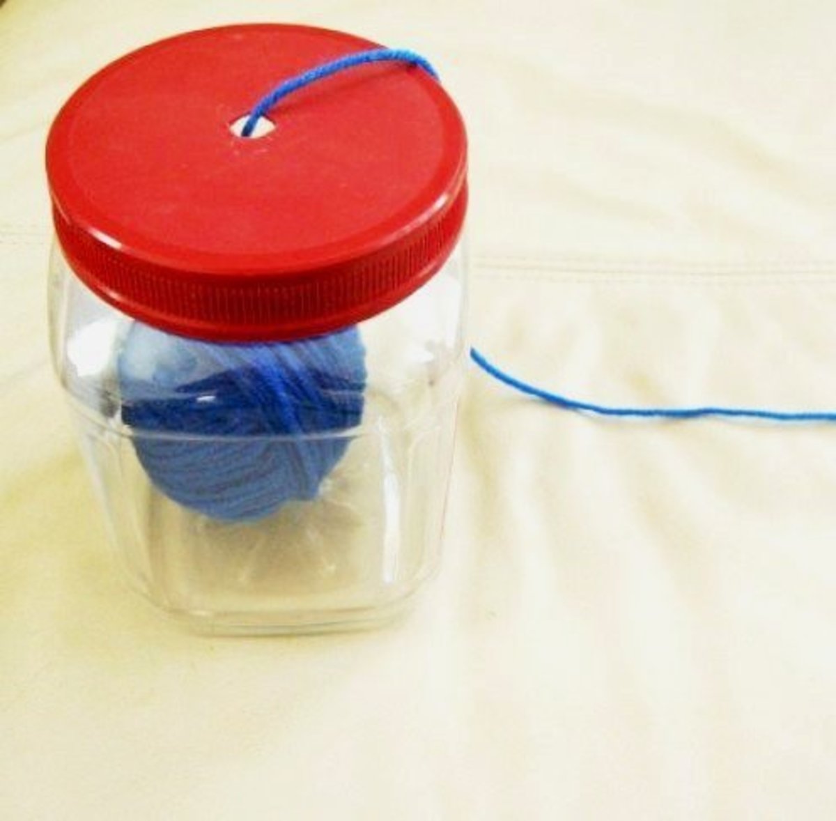 This functional yarn holder is made from a sturdy plastic container.
