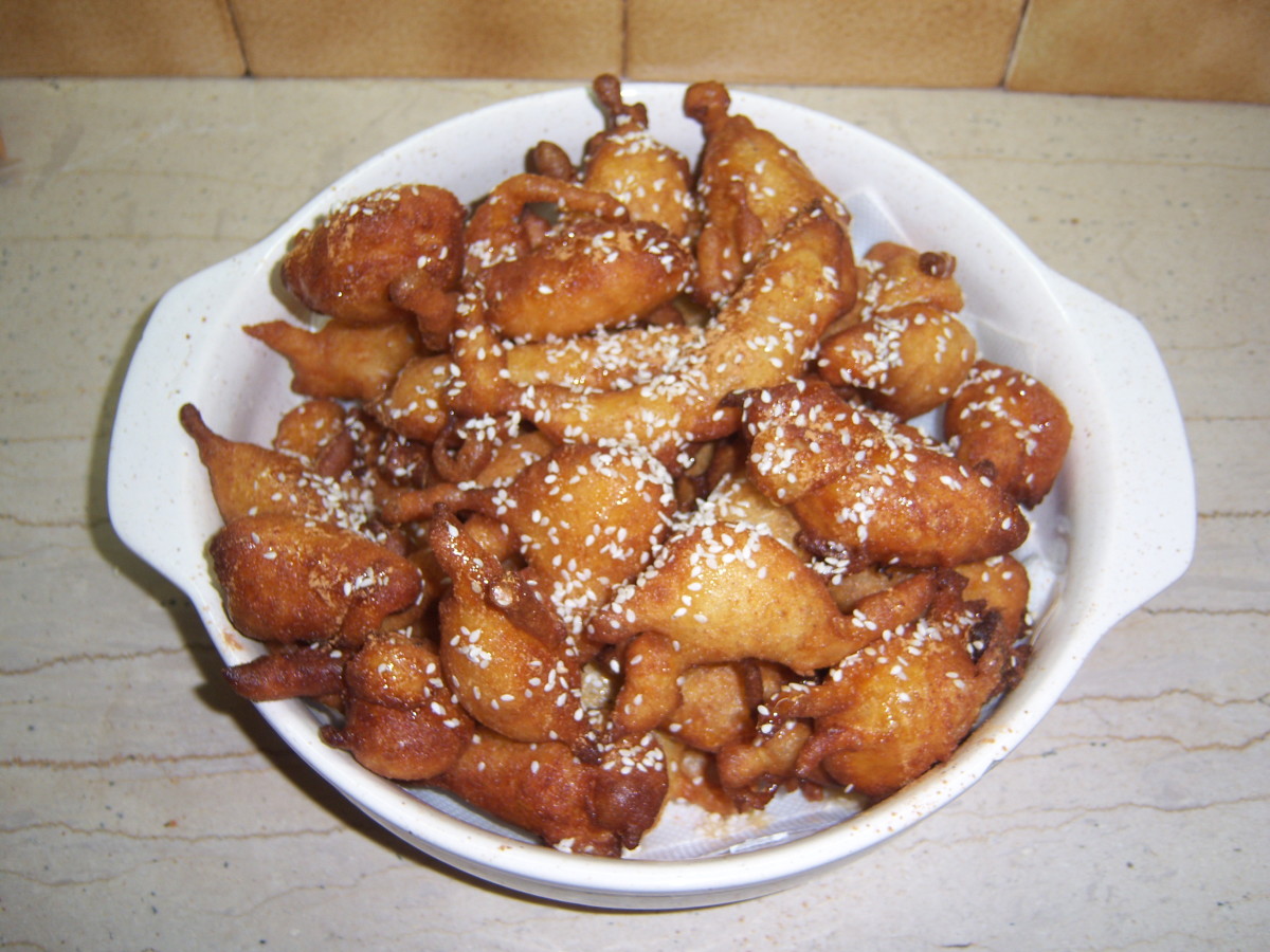 Greek-style doughnuts (loukoumades) drizzled with warm honey and sprinkled with cinnamon and sesame seeds.
