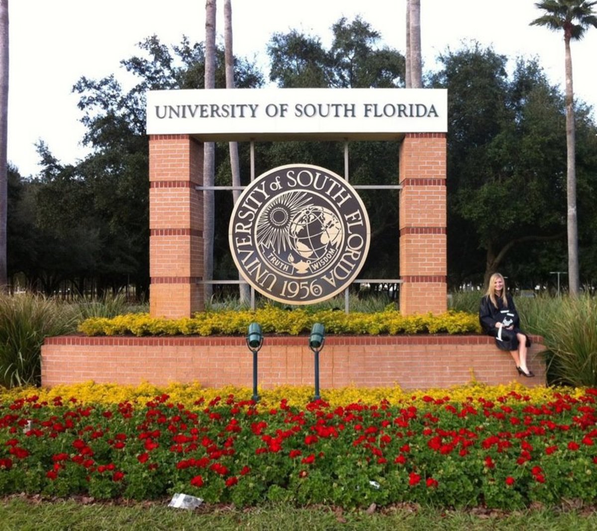 The graduate in front of the University of South Florida sign.