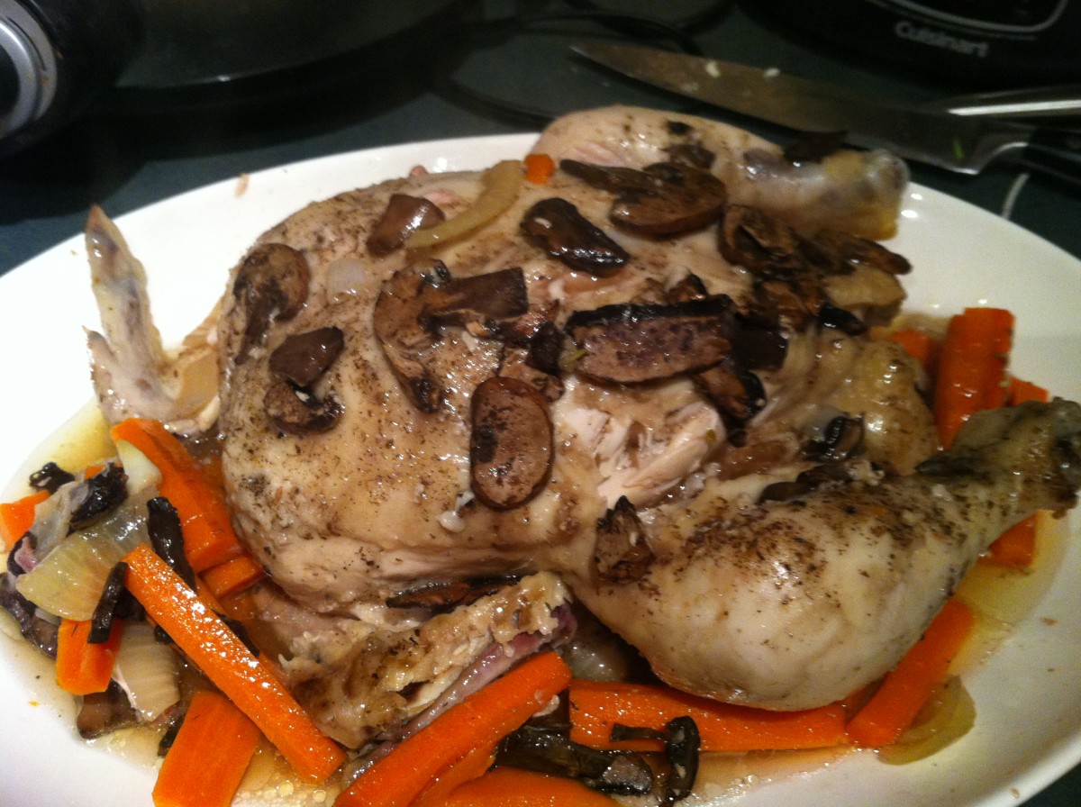 Whole chicken cooked in a slow cooker, with carrots, onions and cremini mushrooms.
