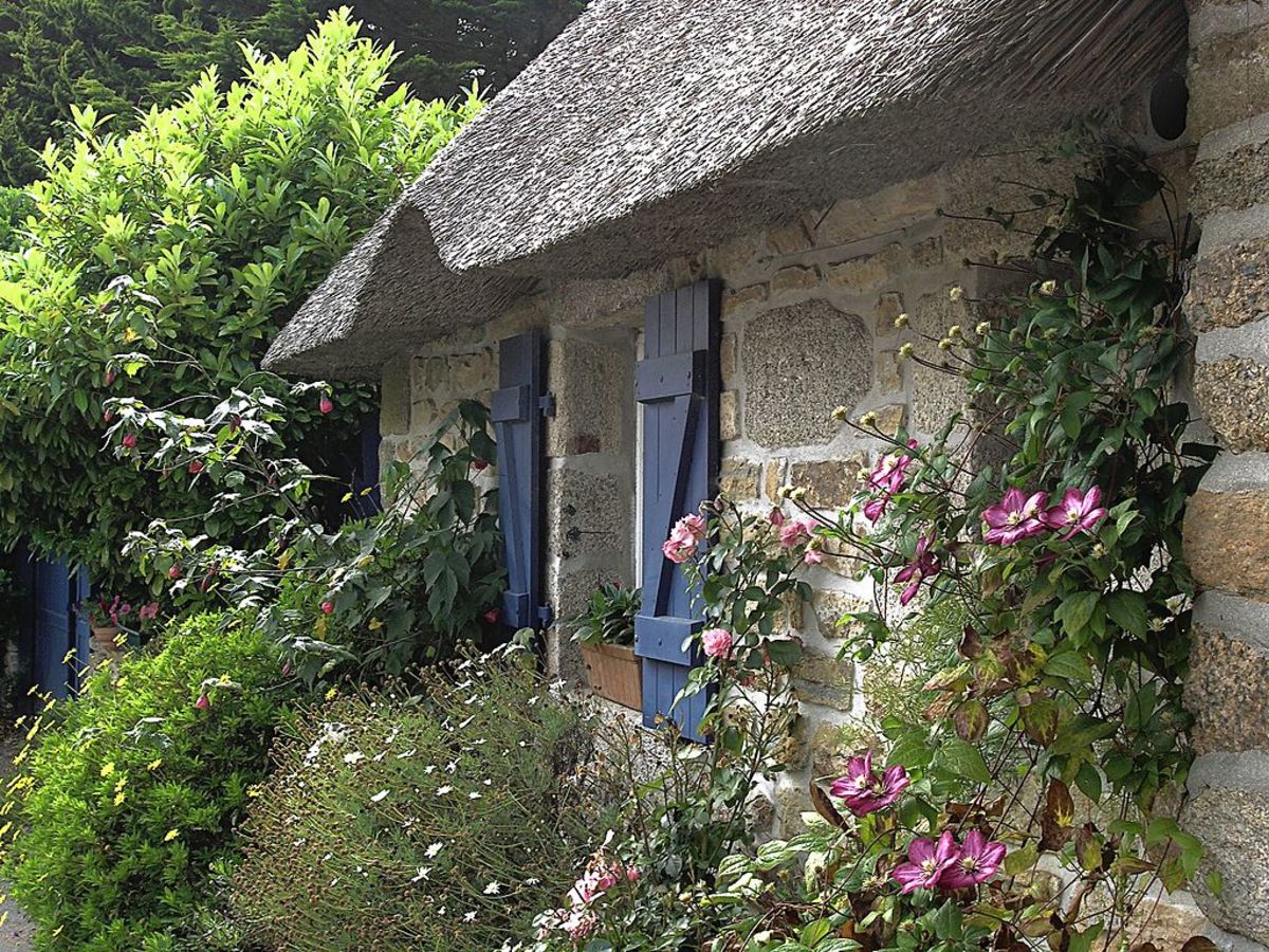 Roses and clematis grow up around the stone dwelling.