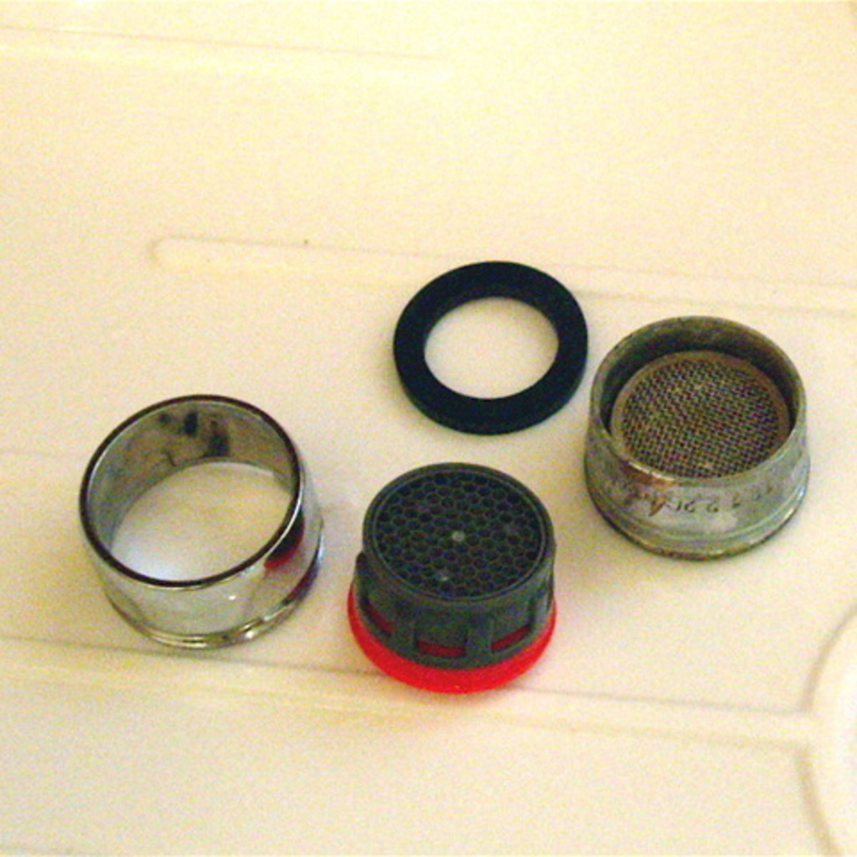 Replace your old faucet aerator with a new, low-flow one. Note that the new one is plastic, whereas the old one is steel mesh that rusted.