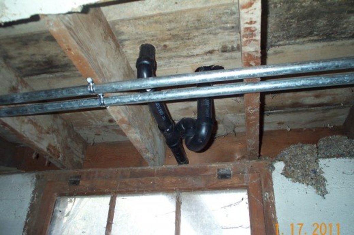 The finished plumbing under the bathroom (including the drain for both sink and bathtub). The galvanized pipes running toward the left go directly through the floor to the pump.