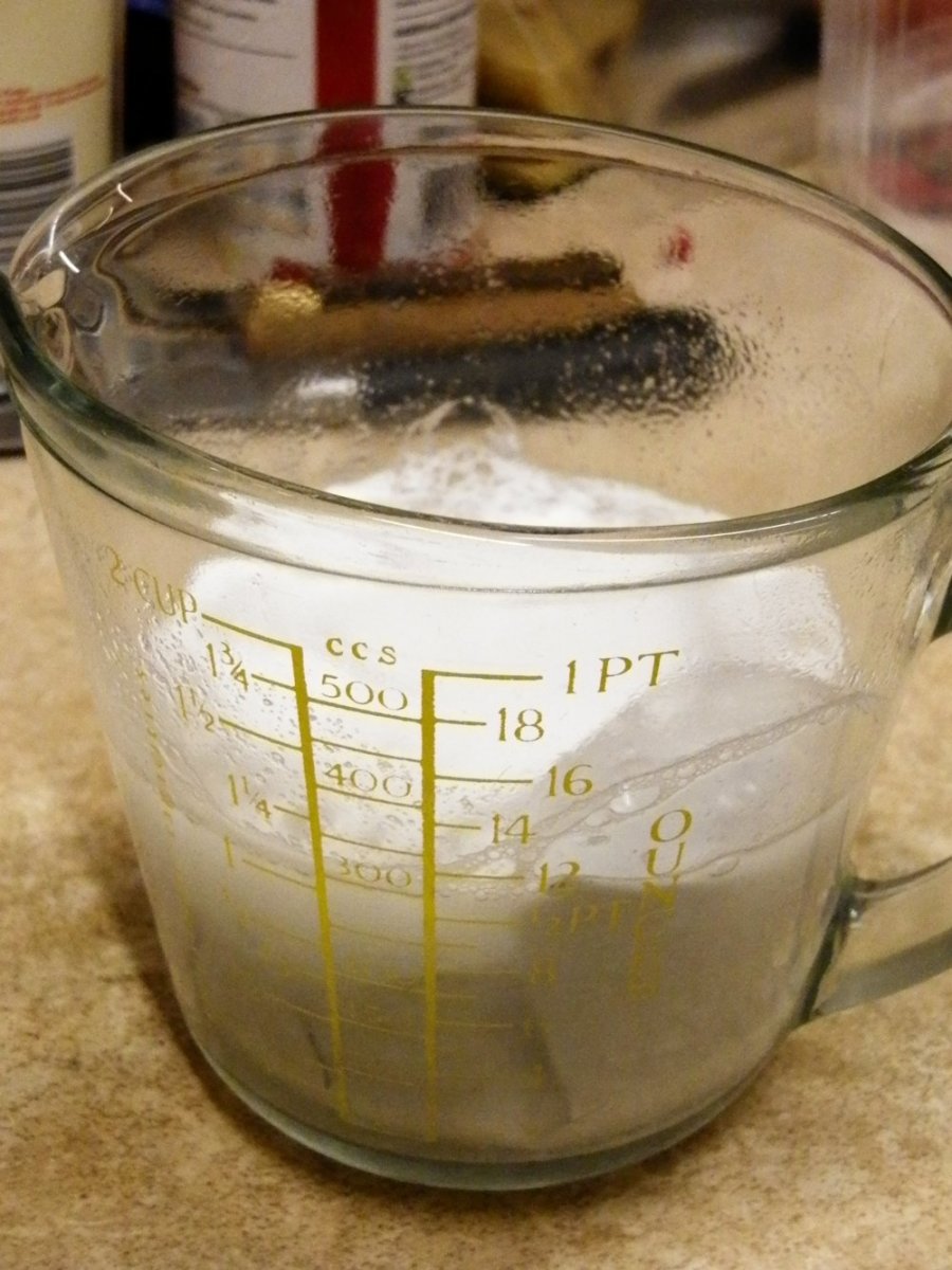 A frothy solution of soda crystals, hot water and aluminium foil in a glass measuring jug.
