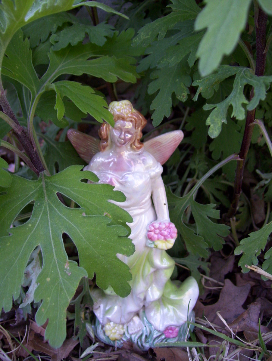 A dollar store fairy figurine guards the chrysanthemums.