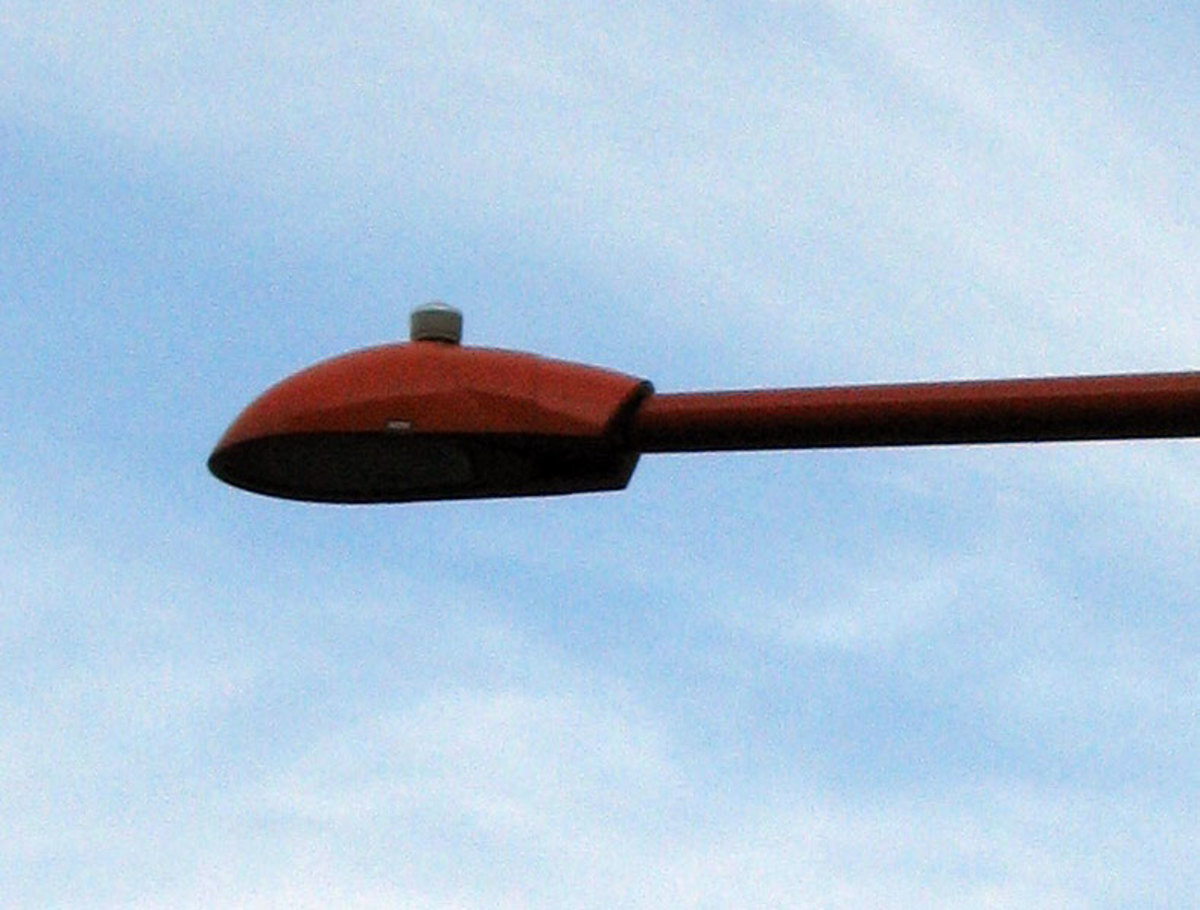 A cobra-head luminaire with a photocell on top (cylindrical object).