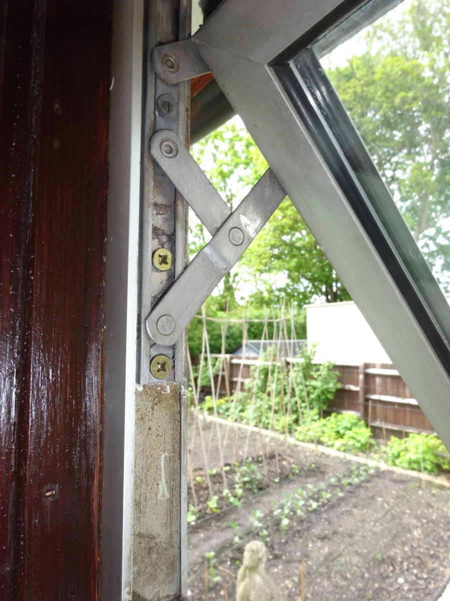 Using sturdy wood screws through predrilled holes in the aluminium to securely anchor the hinge into the wooden frame