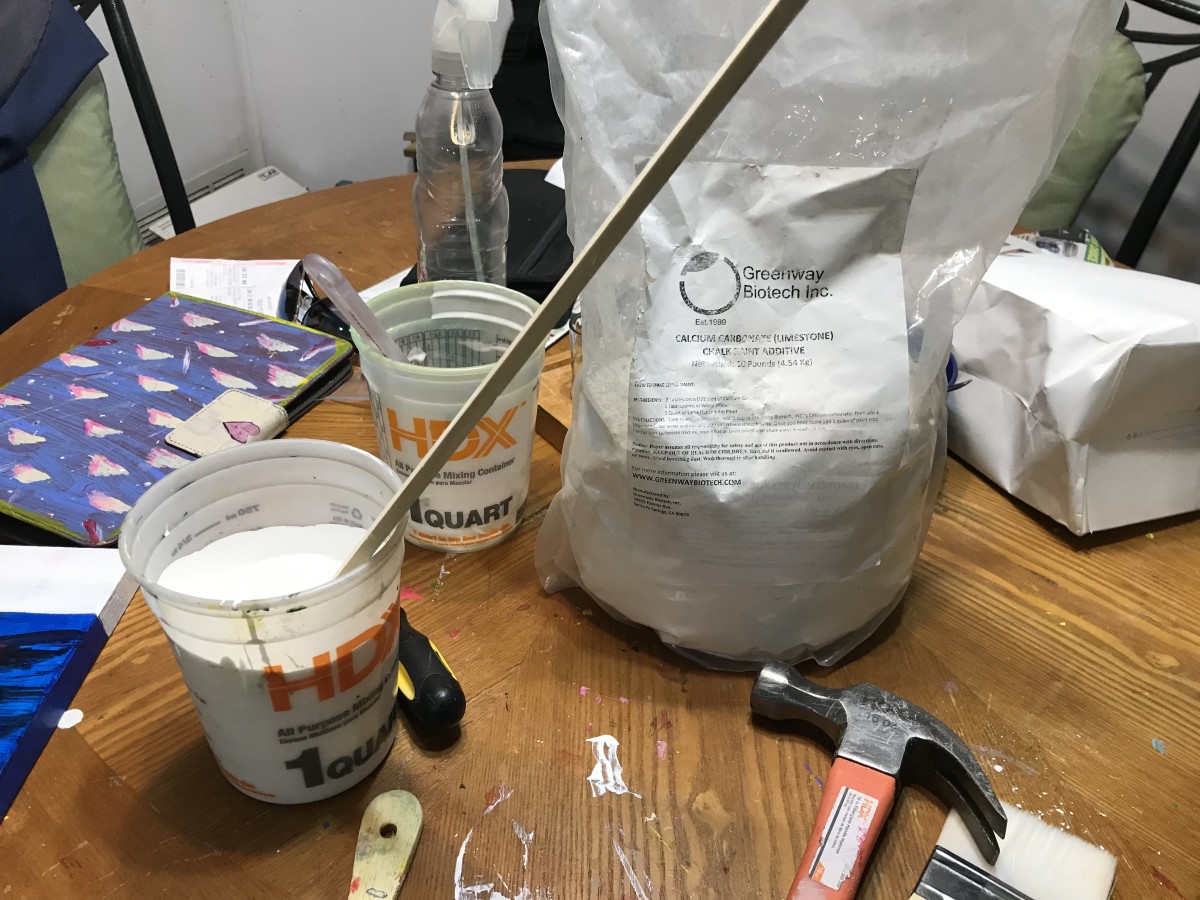 Bag of calcium carbonate shown with a paint bucket full of white latex paint