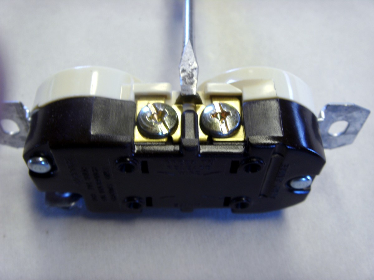 The tip of the small screwdriver is resting on the tab that needs breaking off for a half hot outlet.  This tab provides an electrical connection between the two screws and must be removed to allow the two plug in spots to operate independently