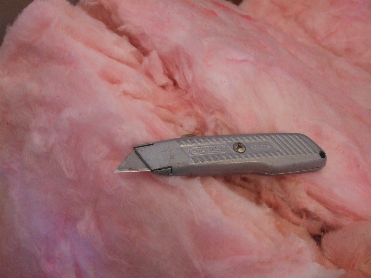 A utility knife rests on a "Pink Panther" fiberglass insualtion roll.