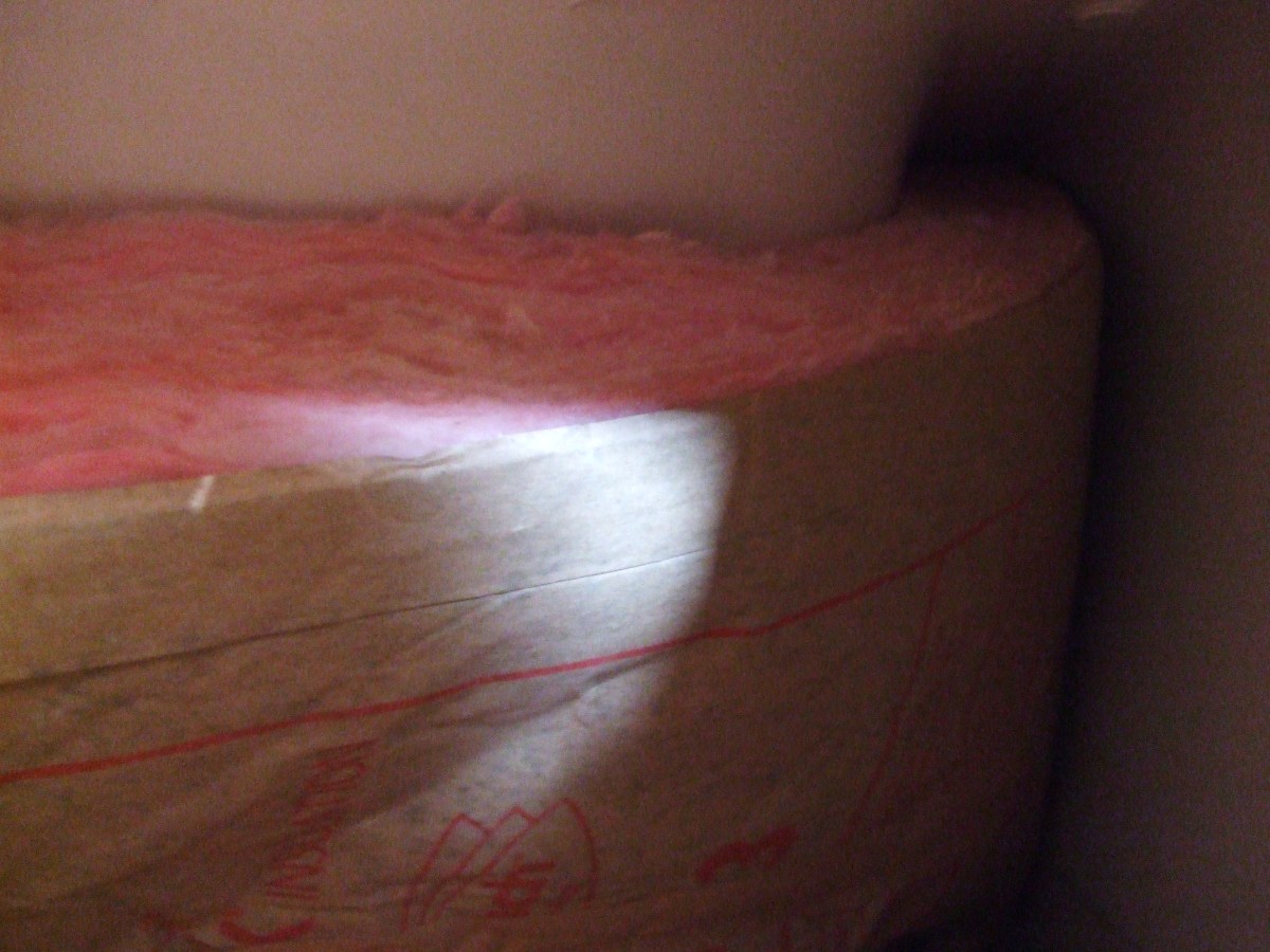 A roll of fiberglass insulation around a tub end.