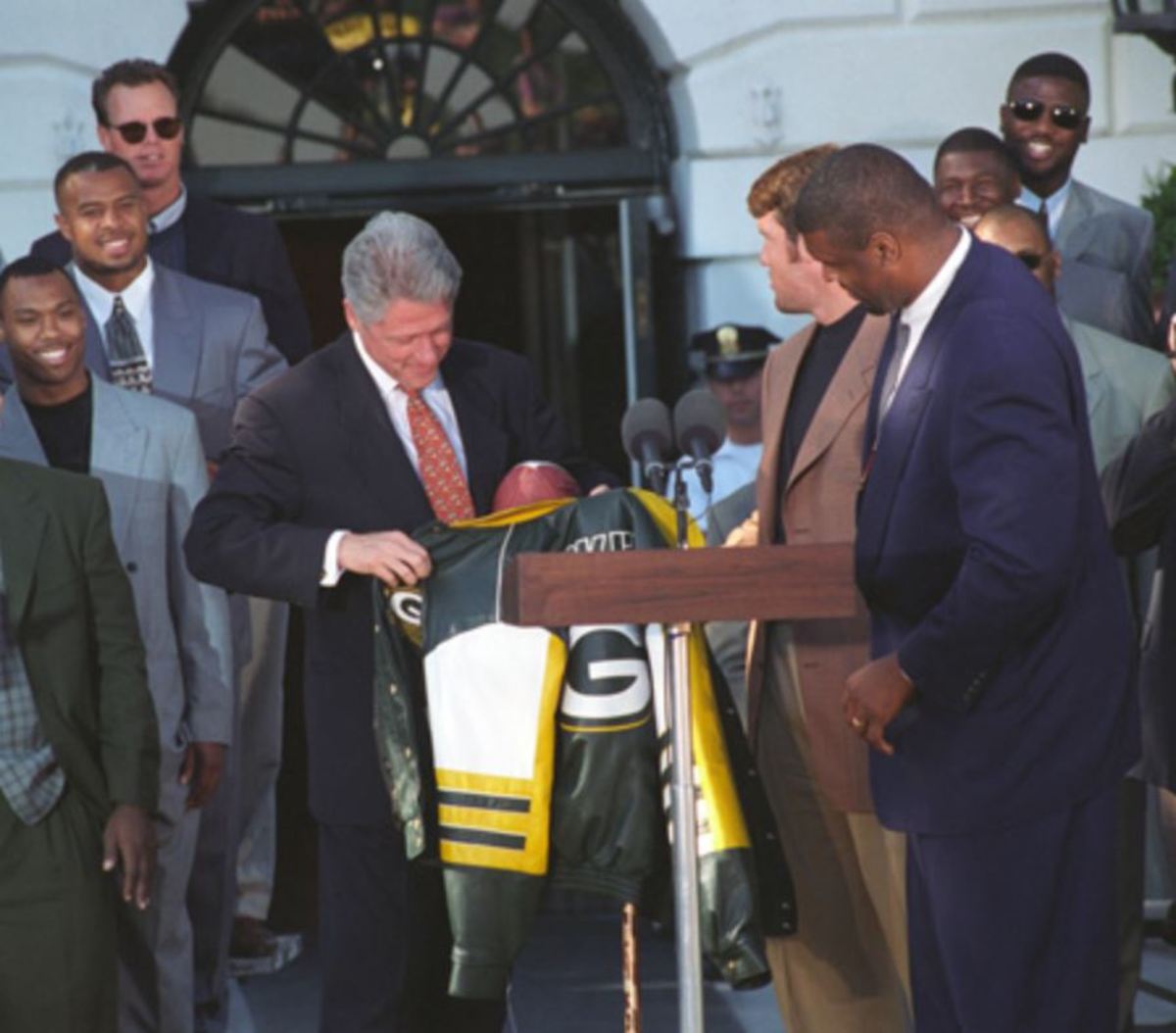 Reggie White and Brett Favre presenting a Green Bay Packers jacket to President Clinton after winning Superbowl XXXI