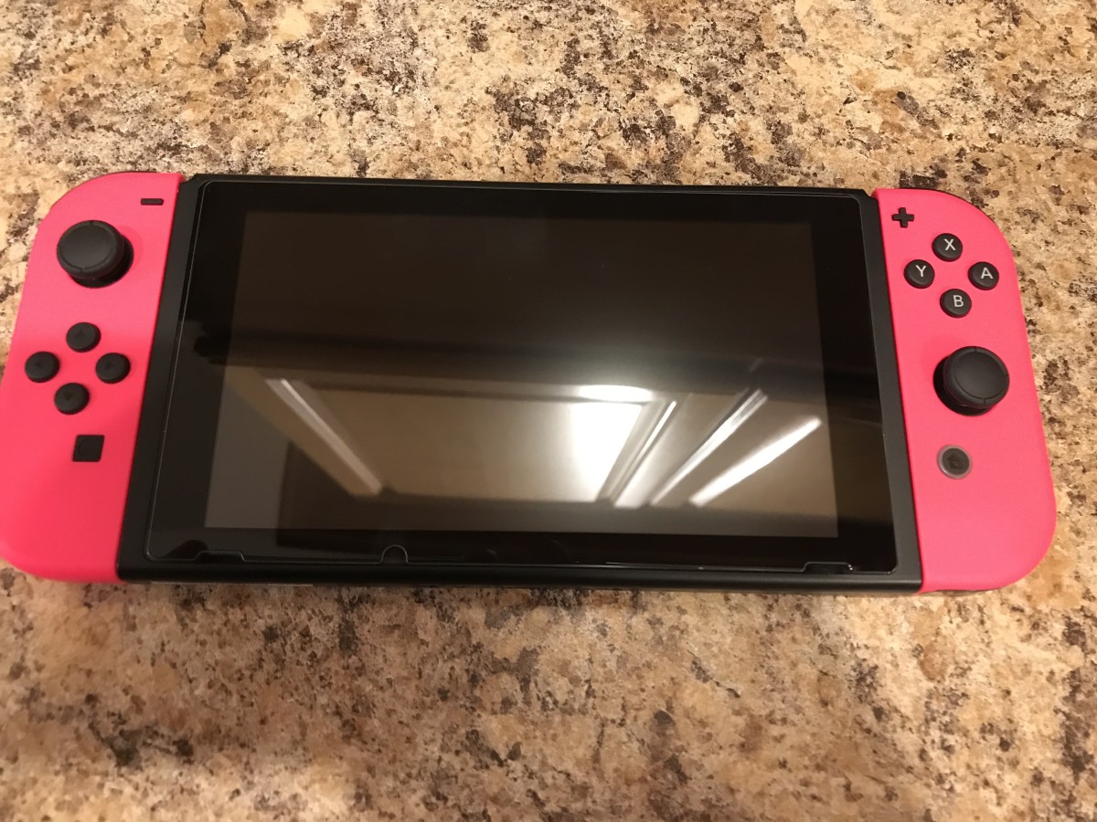 A Nintendo Switch with a glass screen protector and two neon pink Joy-Cons.