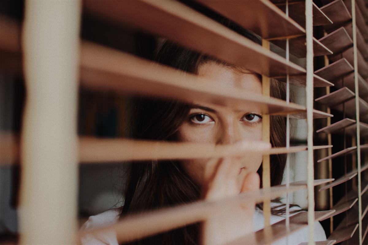 woman peeking through blinds